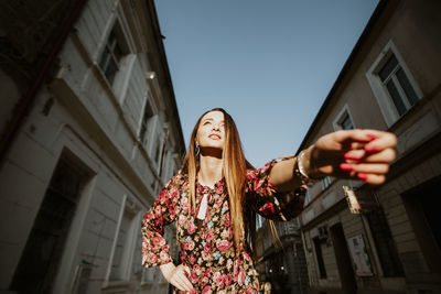 Low angle view of woman looking away while standing in city