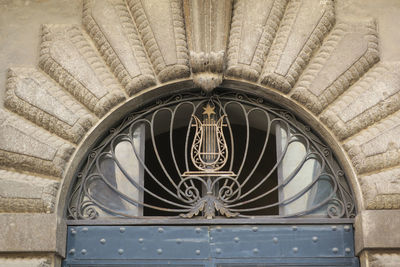 An iron gold painted harp with a golden star on a decorated fence above a frontdoor