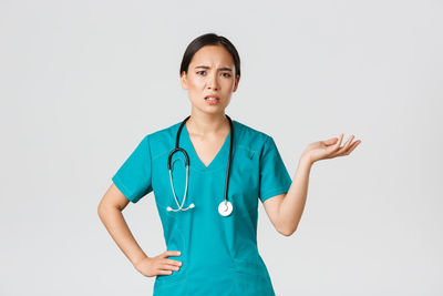 Portrait of young woman standing against white background