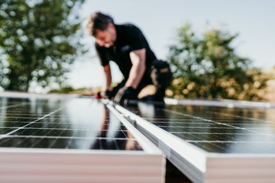 Mature technician man assembling solar panels on house roof for self consumption.focus on foreground