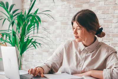 Young woman using laptop while sitting on table
