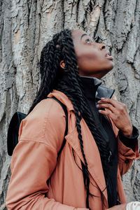 Midsection of woman looking at tree trunk