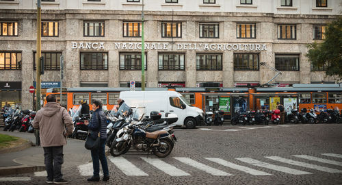 People on street against buildings in city