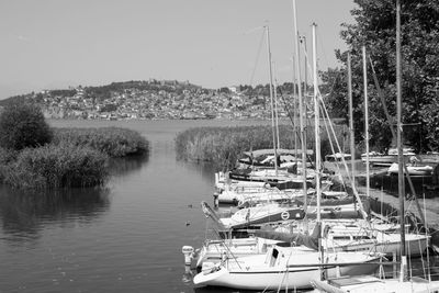 Sailboats moored on lake against sky