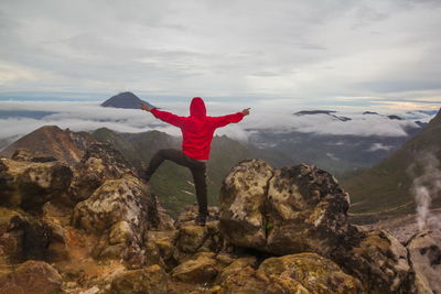 Rear view of man standing on rock against sky