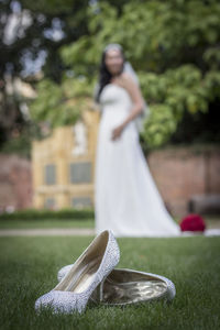 Shoes on grass with bride standing in background