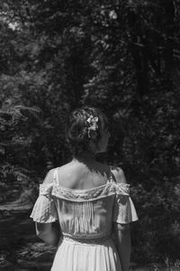 Rear view of woman standing by trees in forest