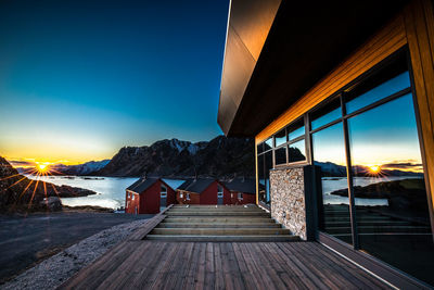 Rear view of man walking on pier against sky during sunset