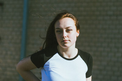 Portrait of young woman standing against wall