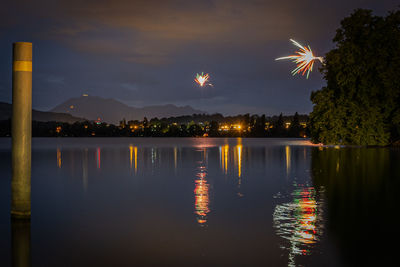 Reflection of illuminated bridge over river against sky at night