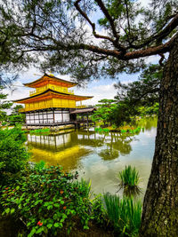 Gazebo by lake and trees against sky