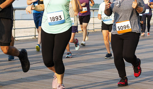 Many runners on a boardwalk are racing a 10k on a summer night at sunken meadow state park.