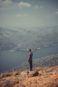 Side view of man looking at lake against sky