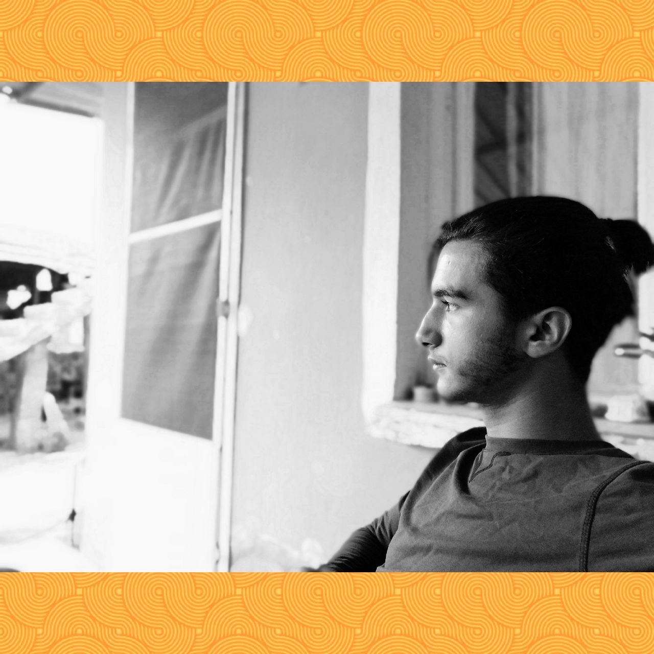 PORTRAIT OF YOUNG MAN LOOKING AWAY WHILE SITTING IN FRONT OF WALL