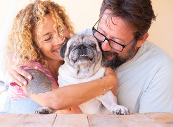 Mature couple embracing pug at table