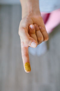 Unrecognizable child showing finger covered of golden glitter composed by harmful small plastics