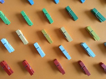 High angle view of colorful wooden clothespins arranged on brown background