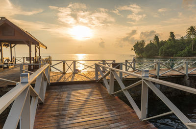 Pier over sea against sky during sunset