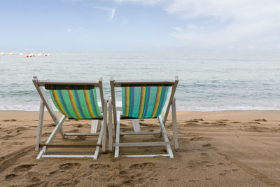 Chairs on beach against sky