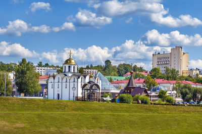 Trees and houses on field against sky