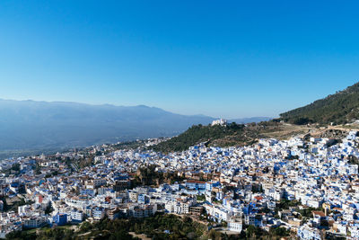 Aerial view of townscape against blue sky