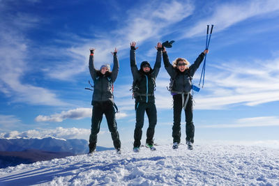 Group of friends jump on snow covered landscape