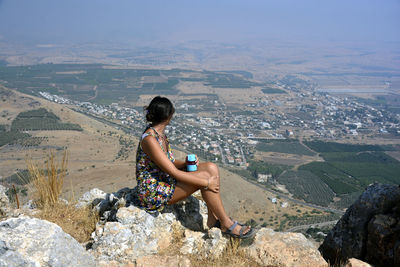 Woman sitting on rock looking at mountains