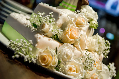 Close-up of wedding cake decorated with roses on table