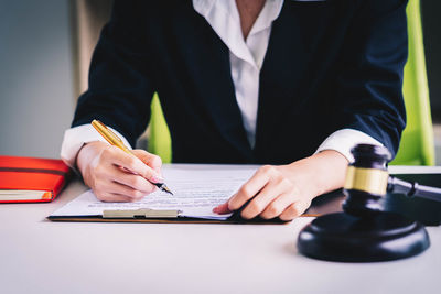 Midsection of man holding paper while sitting on table