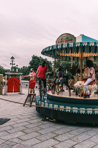 People at amusement park against sky