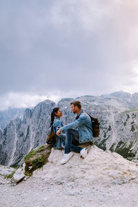 Men sitting on mountain against sky