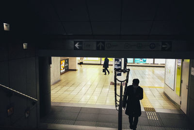 Rear view of man walking on railroad station platform