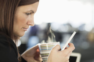 Businesswoman text messaging while having coffee in office