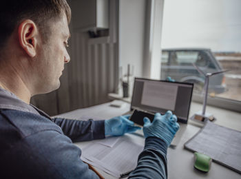 Side view of man using digital tablet while sitting on table