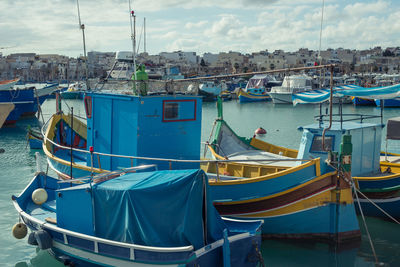 Boats moored at harbor against sky