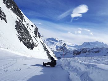 Man skiing on snowcapped mountain against sky