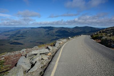 Road leading towards mountains against sky