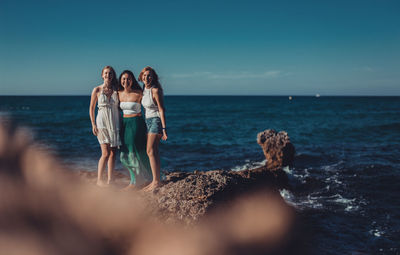 Female friends standing at beach against sky