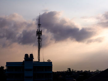 Low angle view of communications tower against cloudy sky
