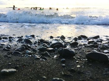 Close-up of pebbles on beach against sky during sunset