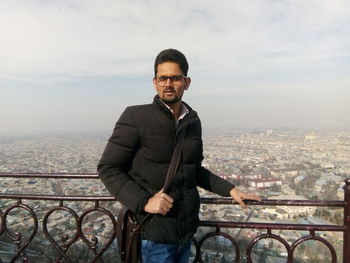 Portrait of young man standing against cityscape