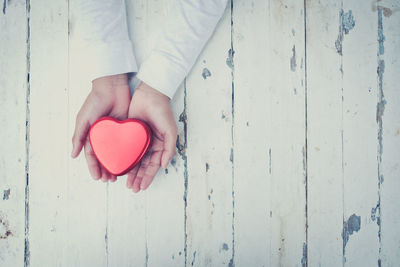 Cropped image of person holding heart shape object over table