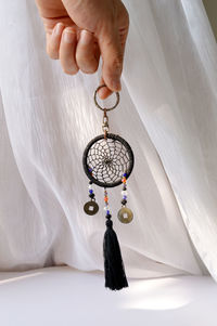 Mini black handmade dreamcatcher in background of a white voile curtain