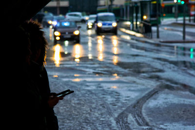 Reflection of woman on car windshield in illuminated city during winter