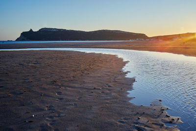 Scenic view of beach against clear sky during sunset