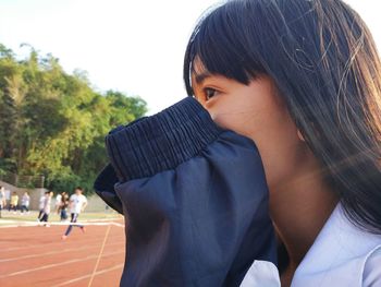 Close-up of woman covering face with tracksuit