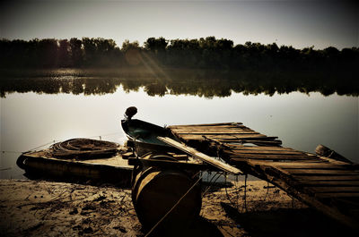 Boat moored by pier on lake against sky