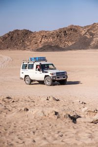 Vintage car on desert land against clear sky
