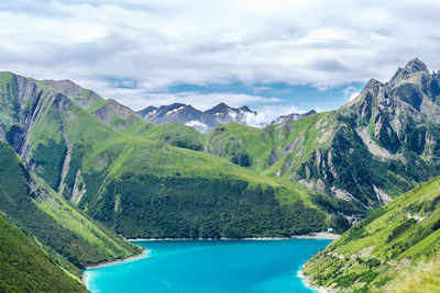 Scenic view of lac de grand maison amidst rocky mountains against cloudy sky