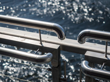 Close-up of metal railing in front of water